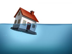 Sinking home and housing crisis with a house in the water on a white background showing the real estate housing concept of flood insurance
