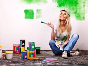 Happy woman paint wall at home to show interior decorating trends in 2018