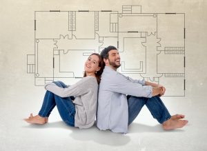 Young attractive couple in love happy together thinking and imaging blueprints , floor plan and design of new house, home, flat or apartment in real state concept to show real estate trend