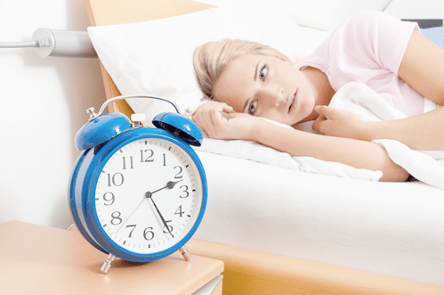 A woman in bed looking at a clock to illustrate trouble sleeping